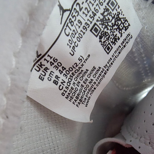 Close-up of a shoe label with text and a QR code on a textured surface.